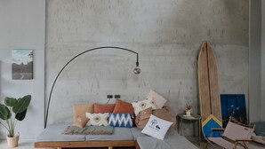 A modern bedroom with a bed, a large abstract painting, a surfboard, and a potted plant. - Slack BnB - Hostel (Liuqiu)