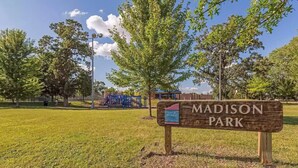 A sign for Madison Park with a playground in the background.