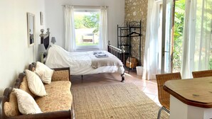 A bedroom with a bed, a sofa, a small table, and a window with curtains.