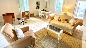Una sala de estar acogedora con sofá, sillones, una mesa de centro y un comedor con mesa y sillas.
