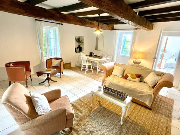 A cozy living room with a sofa, armchairs, a coffee table, and a dining area with a table and chairs.