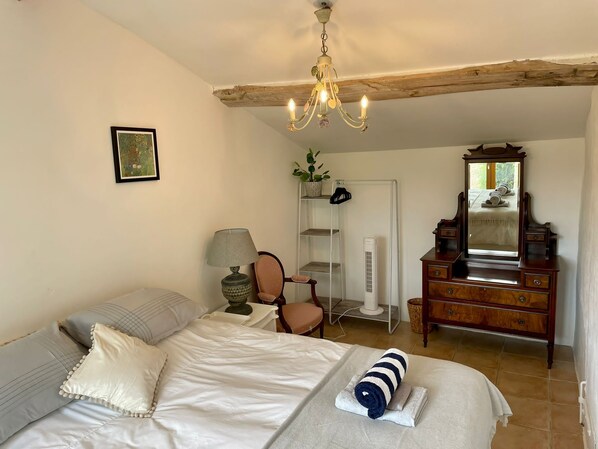 A bedroom with a bed, a dresser, a chair, a lamp, a mirror, and a radiator.