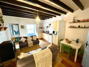 A compact living space with a sofa, a dining table, and a kitchenette. - Golden Fig Sleeps 6 with Pool (Eymet)