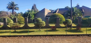 Set amidst a beautifully maintained garden with palm trees, this property boasts a unique curved roof and flat facade.