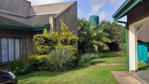 A residential property with a well-maintained garden, a water tank, and a thatched-roof structure. - The Best Green Garden Guest House Harare (Harare)