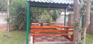 Un banc en bois, placé sous une tonnelle verdoyante, avec une bouteille de vin posée dessus.