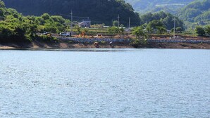 A riverside view with a stone wall, trees, and a few buildings in the background. - 시골냄새가득하고 조금 불편하지만 옛날감성의 숙소 (Yecheon-gun, Gyeongsangbuk-do)