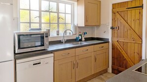 A kitchen with a window, wooden cabinets, a microwave, and a dishwasher.