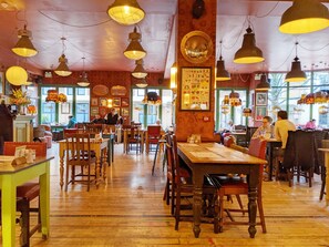 A restaurant with wooden tables and chairs, hanging pendant lights, and large windows. - Vane Cottage - Lewes - a country house that sleeps 4 guests in 2 bedrooms (Lewes)
