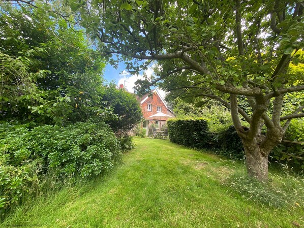A well-maintained garden path leading to a house with a red roof, surrounded by lush greenery and trees. - Vane Cottage - Lewes - a country house that sleeps 4 guests in 2 bedrooms (Lewes)