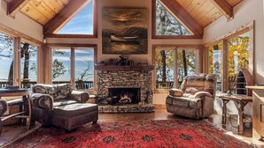 A spacious living room with a stone fireplace, leather sofas, and a red patterned rug. - Enjoy mountain views, cook out on the Weber grill & relax! - Canoe Believe It (Jasper)