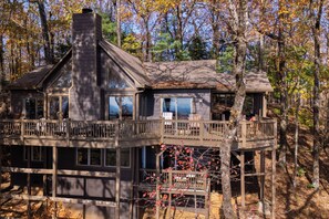 Une cabane dotée de plusieurs terrasses et de grandes fenêtres, entourée d’arbres.