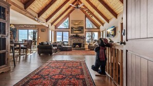 A spacious living room with a high ceiling, a fireplace, and large windows. - Enjoy mountain views, cook out on the Weber grill & relax! - Canoe Believe It (Jasper)