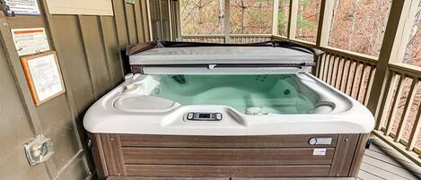 A hot tub on a wooden deck with a wooden bench in front.