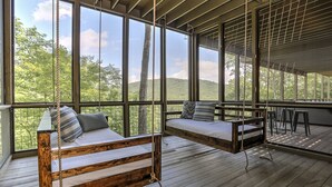 A spacious room with large windows, a wooden swing bed, and a seating area with a view of the outdoors. - Fireside Sips, Soothing Hot Tub Soaks, Hiking Trails, Lakeside Dining & Scenic Golf - Field of Stars (Jasper)