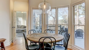 A dining area with a wooden table and chairs, large windows, and a view of the outdoors. - Hillside Manor - Luxury Hot Tub + Fireplace + Pool Table + & Wet Bar (Jasper)