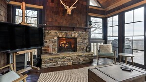A cozy living room with a stone fireplace, a mounted television, and comfortable seating. - MountainView - Mountain luxury in Big Canoe! (Jasper)