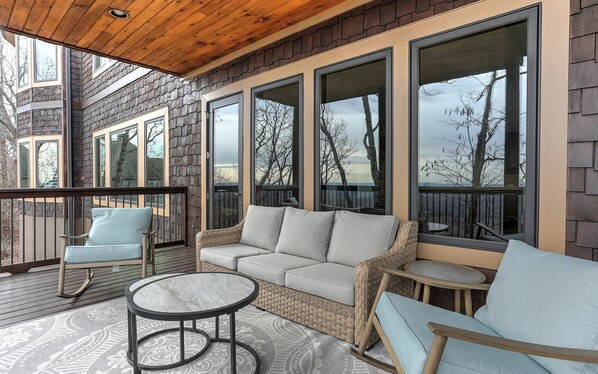 A covered outdoor seating area with a wicker sofa, two chairs, and a small table.