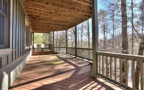 A covered wooden deck with a railing, overlooking a forested area. - Paradise Retreat - Sip Cocktails by Lake Disharoon, Play Golf & Swim Year-Round (Jasper)