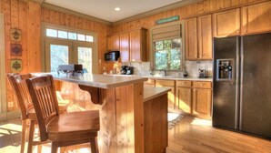 A kitchen with wooden cabinets, a stainless steel refrigerator, a microwave, and a coffee maker. - Paradise Retreat - Sip Cocktails by Lake Disharoon, Play Golf & Swim Year-Round (Jasper)