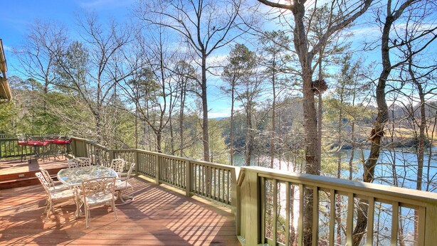 A wooden deck with outdoor furniture, a railing, and a view of a lake surrounded by trees. - Paradise Retreat - Sip Cocktails by Lake Disharoon, Play Golf & Swim Year-Round (Jasper)
