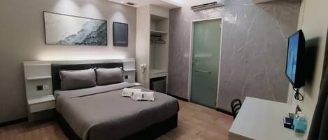 Una habitación de hotel moderna con cama, mesitas de noche, televisor y armario.