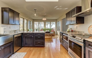 A modern kitchen with dark cabinetry, a central island, and a large stove.