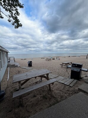 Une plage équipée de tables de pique-nique et d’un barbecue.