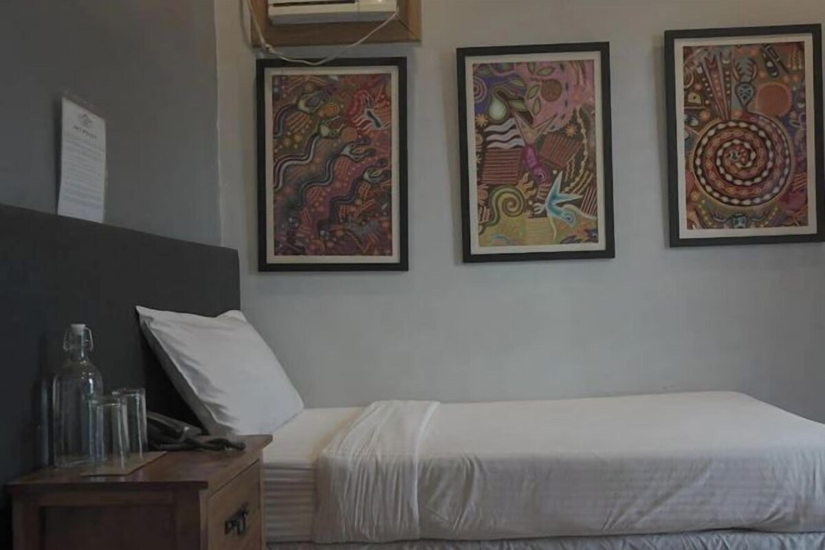 Una habitación de hotel con una cama, una mesita de noche y tres obras de arte enmarcadas en la pared.