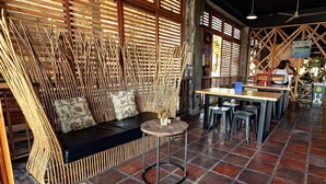 A cozy indoor seating area with a sofa and round tables, bamboo partitions, and a tiled floor. - Casa Alegria Bed and Breakfast Antipolo (Antipolo)