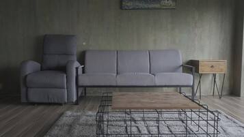 Ein modernes Wohnzimmer mit einem grauen Sofa, einem grauen Sessel, einem Holztisch und einem kleinen Beistelltisch.