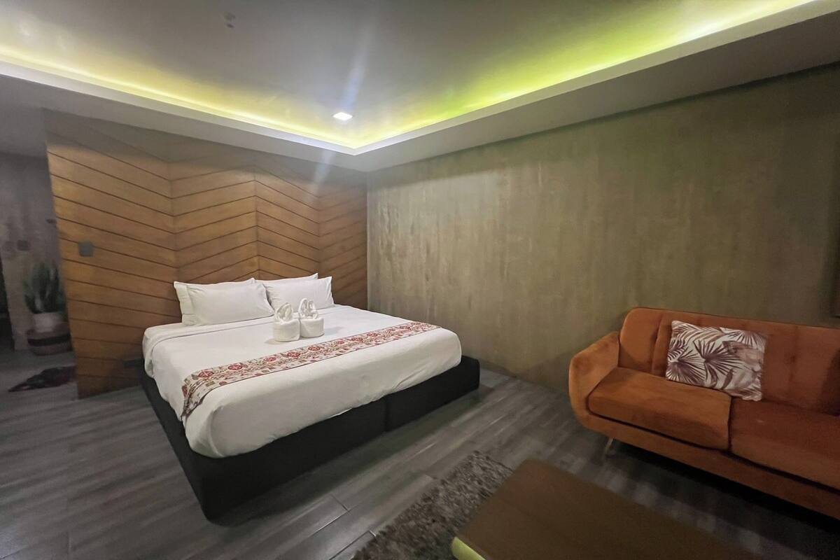 A modern bedroom with a bed, a sofa, and a small table.