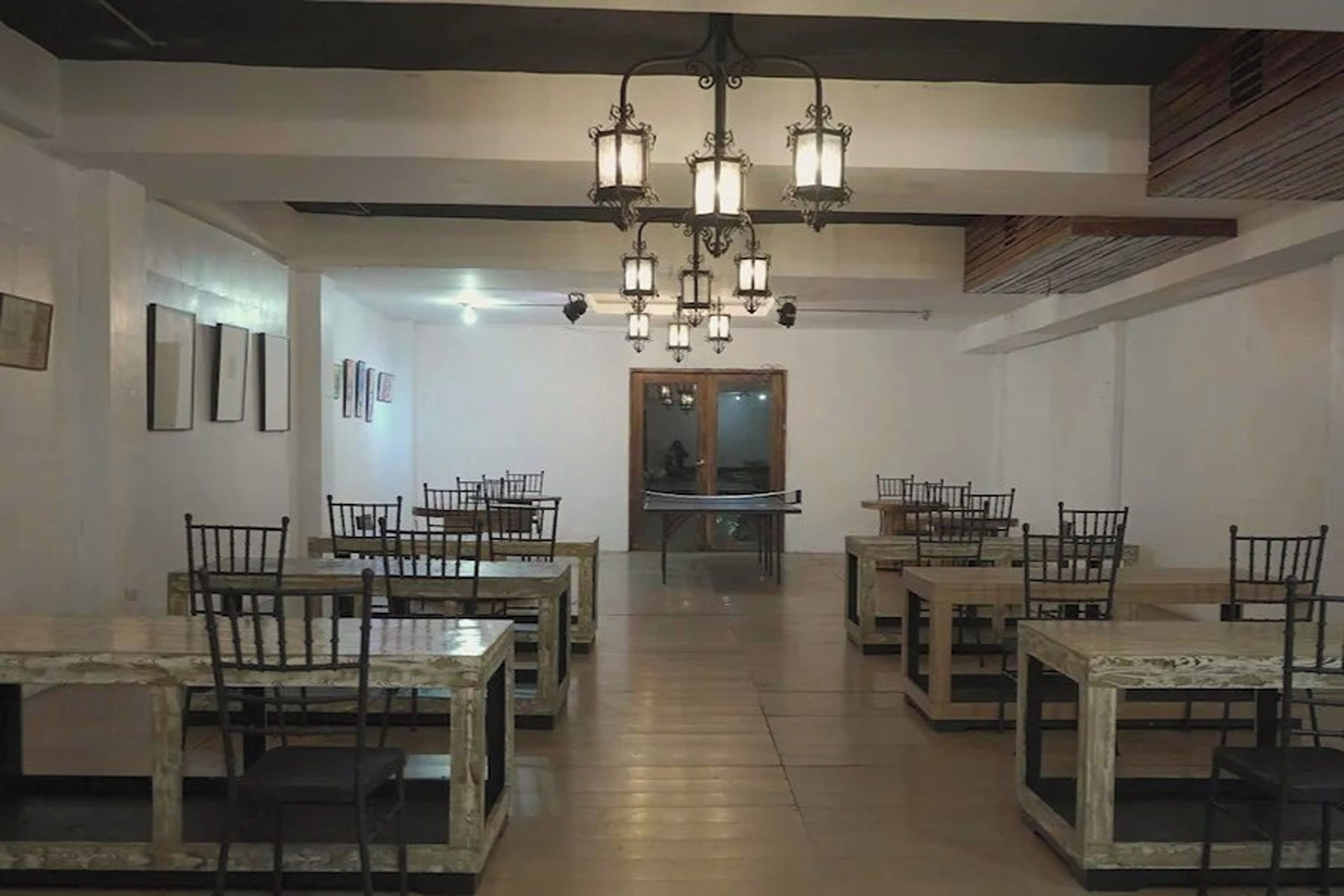 Un comedor con varias mesas y sillas, un candelabro y cuadros en las paredes.