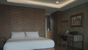 A modern bedroom with a wooden herringbone wall, a bed with white linens, a desk with a chair, and a framed picture on the wall. - Casa Alegria Bed and Breakfast Antipolo (Antipolo)