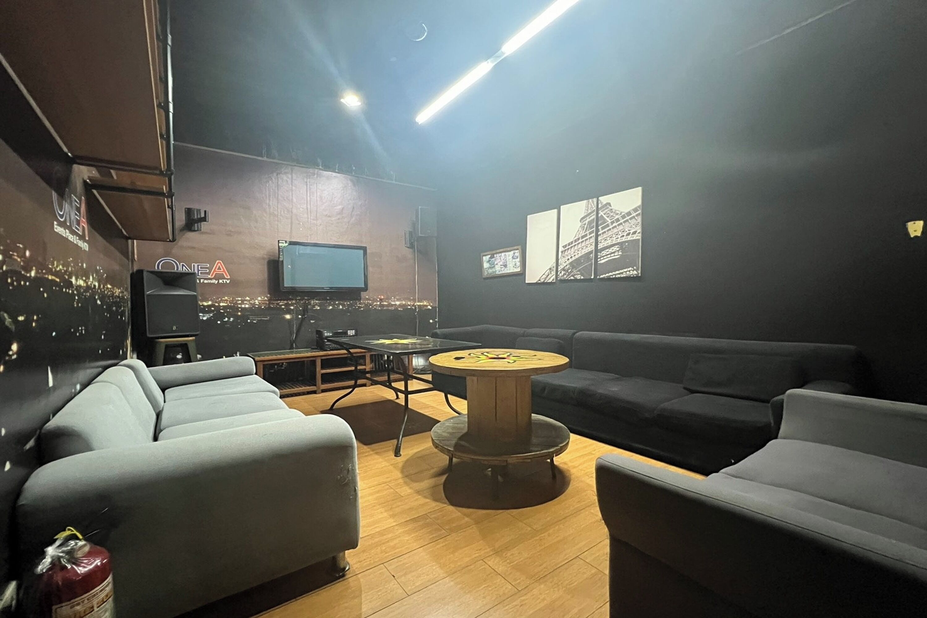 A modern lounge area with a sofa, a round wooden table, and a flat-screen TV mounted on the wall.
