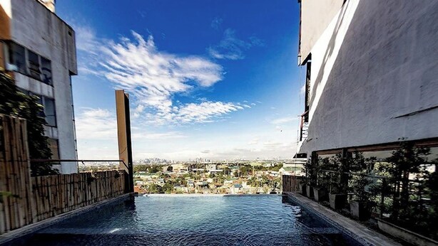 An infinity pool with a city view, surrounded by modern buildings. - Casa Alegria Bed and Breakfast Antipolo (Antipolo)
