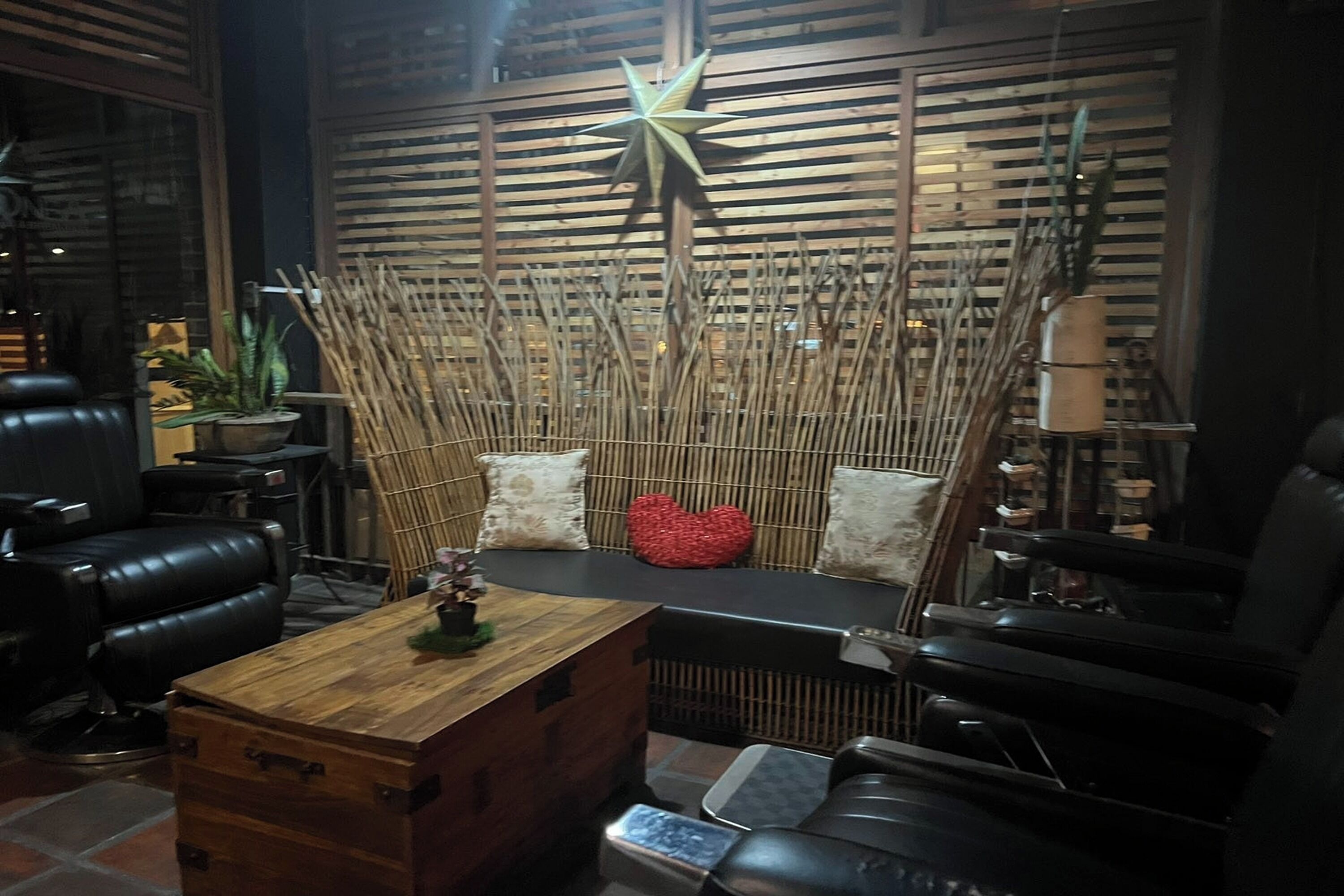 Un interior moderno con un mostrador de recepción de madera, asientos de cuero negro y una pared decorativa de bambú.