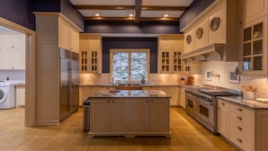 A spacious kitchen with a large island, built-in appliances, and a view of trees through the window.