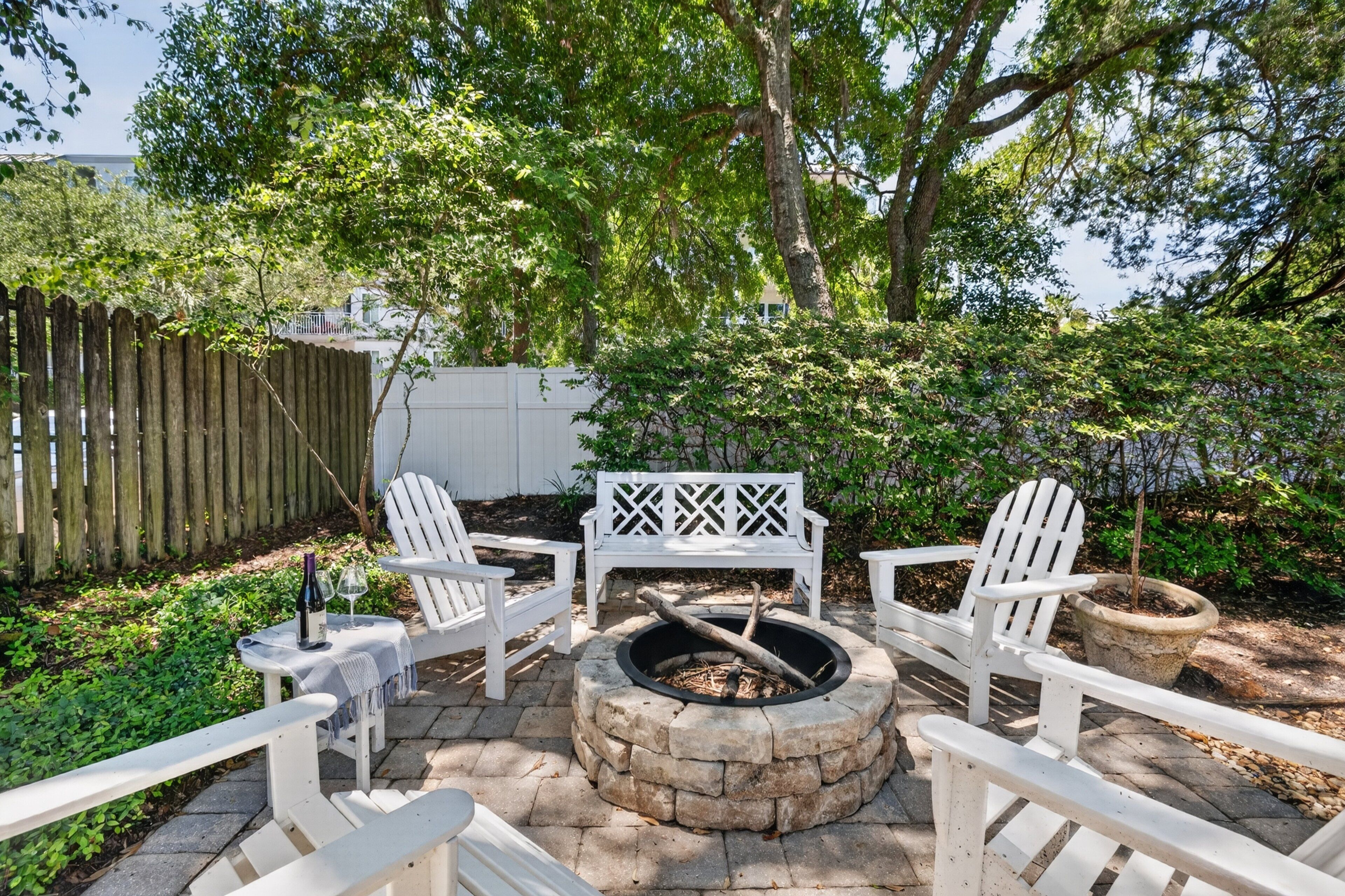 A patio with Adirondack chairs, a fire pit, and a white bench.