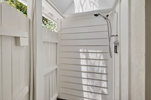 A white wooden door with a showerhead and hose.