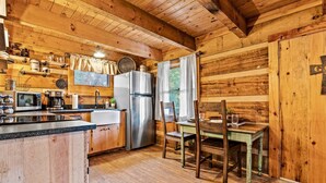 A rustic cabin interior with a kitchen, dining area, and a large window. - Retreat that will have you wanting more RELAxATION (Sevierville)
