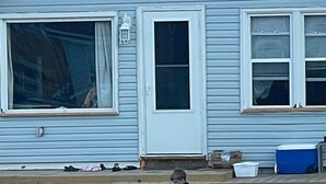 Ein Strandhaus mit großem Fenster, einer Tür und einer Bank.