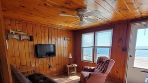 Ein Holzblock-Interieur mit Fernseher, Kamin, Sofa und Sessel.