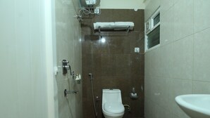 A small, compact bathroom with a toilet, a sink, and a shower. - PPH Living Nagavara Lake Sai Inn (Bengaluru)