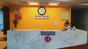 A reception desk with a clock, a "No Smoking" sign, a "SAI SUITES INN" sign, and a "Reception" sign. - PPH Living Nagavara Lake Sai Inn (Bengaluru)