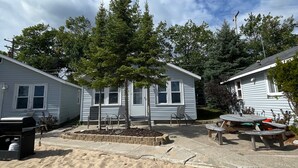 A sandy outdoor area with a picnic table and chairs, surrounded by mobile homes with a tree in the center. - #6 Miami Beach Resort  (Au Sable Charter Township)