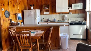 A wooden cabin-style kitchen with a dining table, chairs, a refrigerator, a microwave, a stove, and a ceiling fan. - #6 Miami Beach Resort  (Au Sable Charter Township)