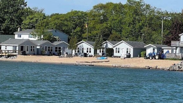 A row of beachside cabins with a sandy beach and a dock. - #6 Miami Beach Resort  (Au Sable Charter Township)