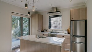Una cucina moderna con isola centrale, elettrodomestici in acciaio inossidabile e un'ampia finestra che permette l'illuminazione naturale.