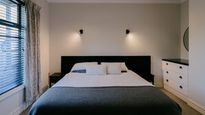 Una camera da letto con un letto, due comodini, una cassettiera e una finestra con tende.